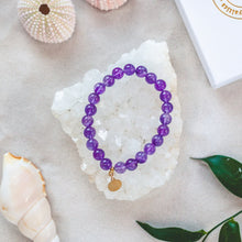 Ladda upp bild till gallerivisning, Elegant and stylish elastic Amethyst bracelet with high grade gemstones and details in 18k gold plated 925 sterling silver and brass. Presented on a crystal cluster and beach.
