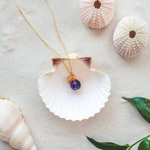 Load image into Gallery viewer, Elegant and minimalistic amethyst necklace with details in 18k gold-plated 925 Sterling silver and brass. Presented in a shell on a beach.
