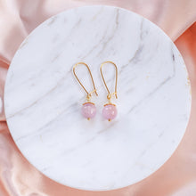 Load image into Gallery viewer, Elegant Kunzite earrings with details in 18k gold-plated 925 sterling silver. Presented on marble and pink silk fabric.
